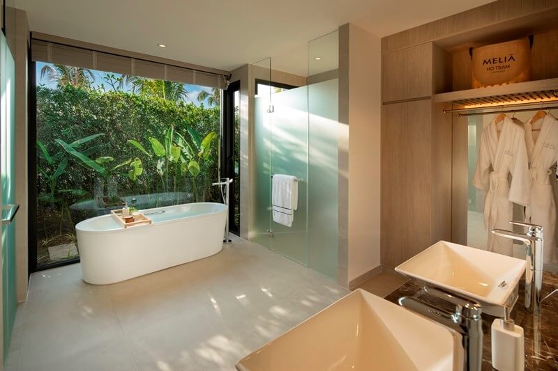 In the villas, floor-to-ceiling glass panels open the bathrooms to private gardens. 