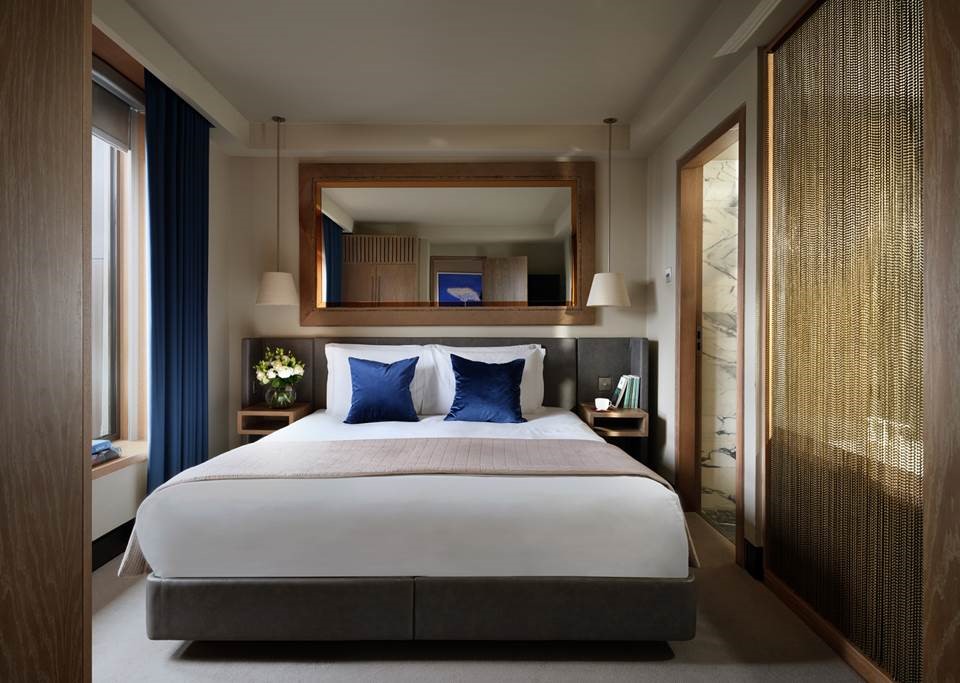 The Hari London's 51sqm Lockhart Suite offers a king bed with custom imported linens and down comforters and pillows, a separate open plan living area, cosy feature fireplace, private library, marble bathroom with enclosed walk-in shower and bathtub and two private balconies overlooking London’s famed skyline.